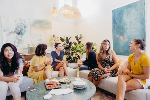 convidados da festa com pratos e taças de vinho em um sofá