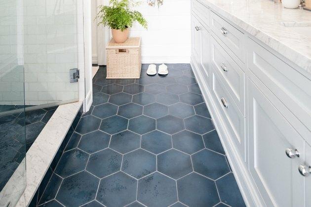 Chão do banheiro com ladrilho azul e planta em uma cesta