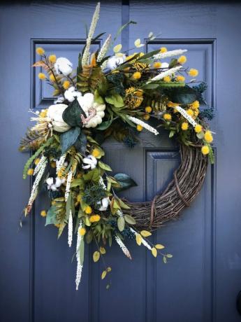 herfstkrans gemaakt met wijnstok, witte pompoenen, gele bloemen en groen