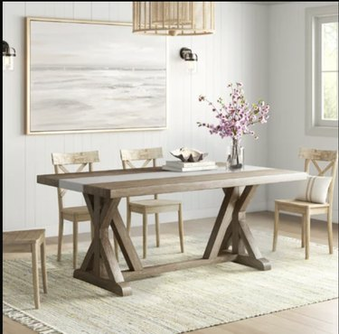 Stačiakampio sodybos stiliaus pietų stalo vaizdas su trimis kėdėmis aplink jį.