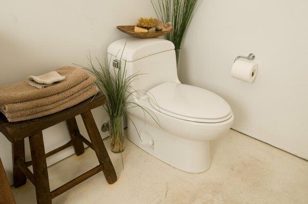 Colț de baie cu toaletă și prosoape pe scaun