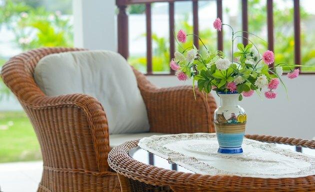 Chaise tissée avec oreiller blanc et vase à fleurs avec fond nature