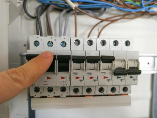 Elektrotechnicus analyseert AC-installatie in schakelkast