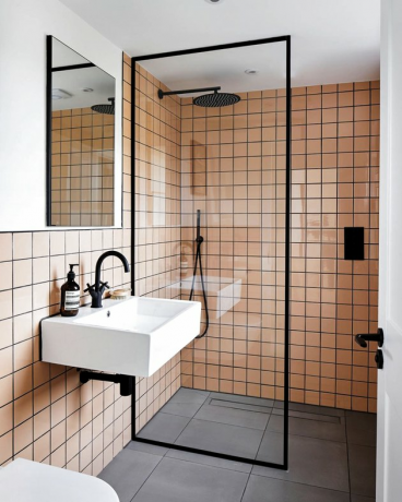 Azulejos rosa com argamassa preta em banheiro moderno com box de chuveiro
