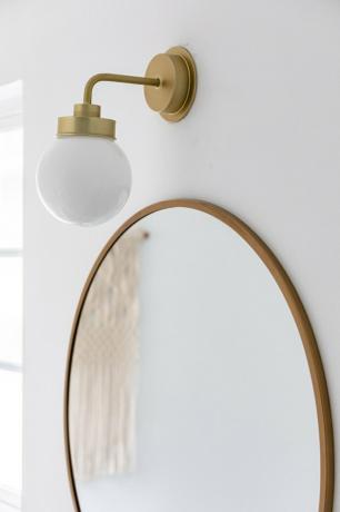 becul de baie se aprinde peste o oglindă circulară cu garnitură de alamă