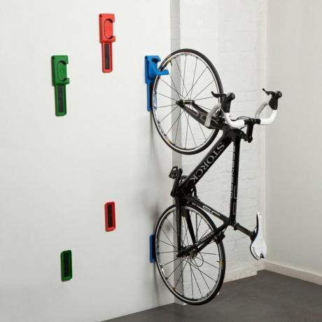 ganchos de armazenamento de bicicleta vermelho, verde e azul segurando uma bicicleta