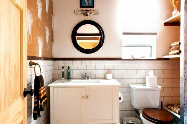 um banheiro com piso de metrô, uma penteadeira de madeira rústica e um estêncil de caveira de vaca na parede