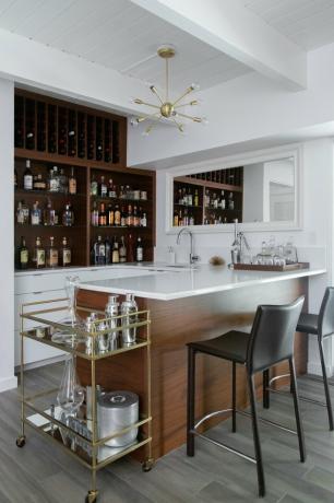 Bar contemporâneo em madeira, construído em estantes de madeira, lustre moderno, carrinho de bar, bancos altos de couro preto.