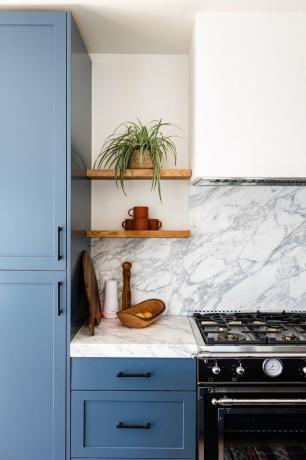 cozinha azul e branca com exaustor de fogão e backsplash de mármore