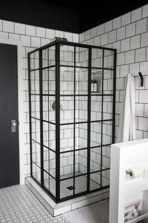 Chuveiro de canto com azulejos brancos e detalhes lineares industriais pretos