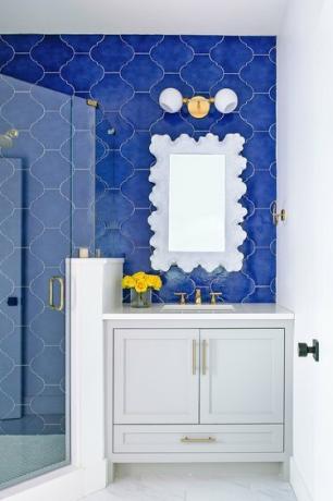 Blauw betegelde badkamer met gouden armaturen en hardware