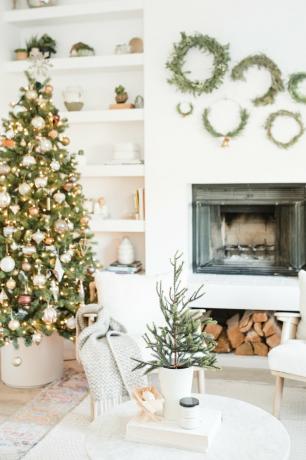 cores de Natal brancas e douradas na lareira da sala com árvore de Natal e decoração boho