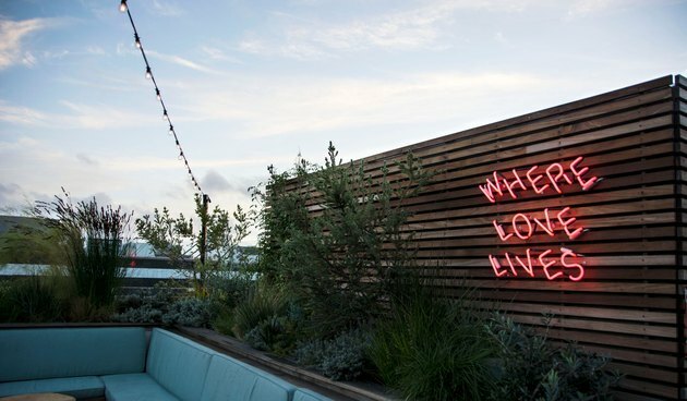 Bar sul tetto con insegna al neon "Where Love Lives".