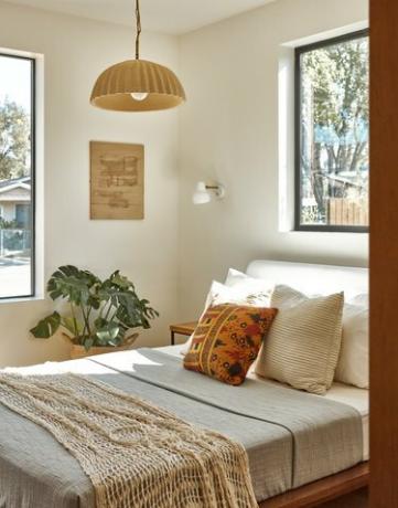 habitación de invitados con lámpara colgante, una planta y dos ventanas
