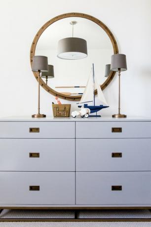 Organização do quarto infantil com cômoda cinza e espelho redondo