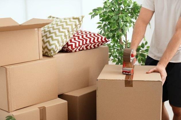 Коробка коробки упаковки человека внутри помещения, крупный план. День переезда