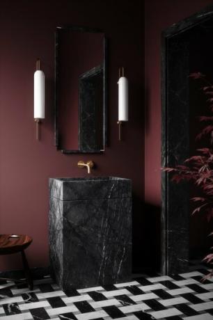 badeværelse med rødbrune vægge, sort stenvask og sort og hvid klinkegulv