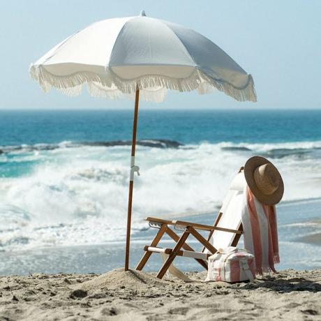 Este guarda-chuva de estilo boho é decorado com franjas brancas antigas que farão com que todos os dias na praia sejam luxuosos. 