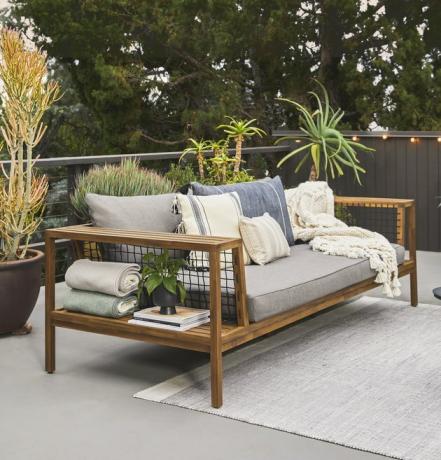 sofá al aire libre con alfombra ligera y plantas cercanas