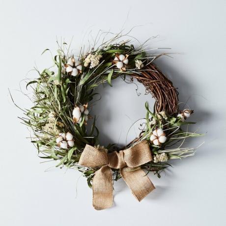 decoração de natal de casa de fazenda com guirlanda de videira com vegetação, botões de algodão e laço de estopa