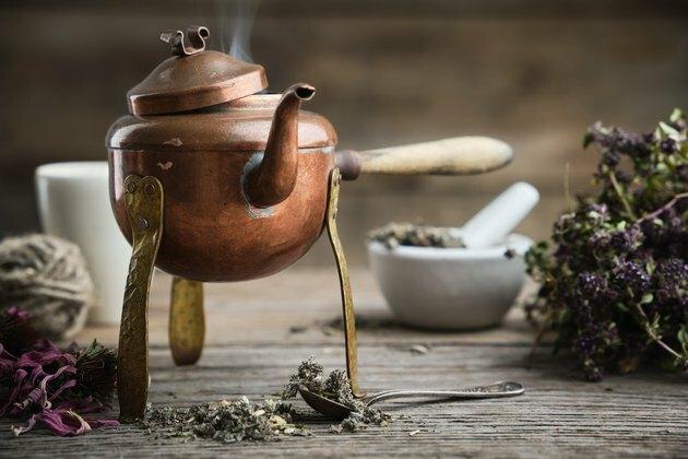 Старый старинный кипящий чайник, ступка, сухие конусоцветы и пучок тимьяна.