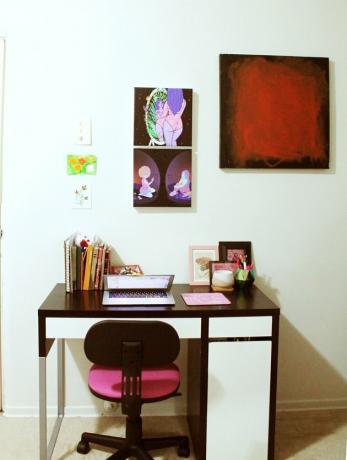 mesa com cadeira rosa e arte na parede