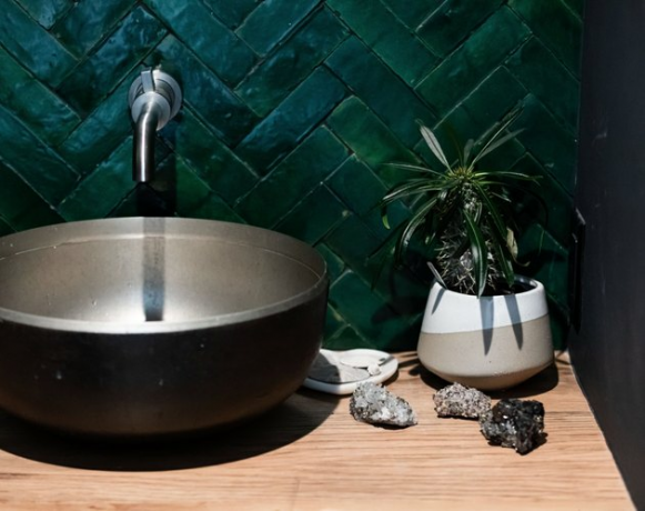 Pia redonda de metal, backsplash de azulejo verde escuro e torneira de banheiro montada na parede