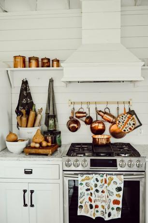 Fall Kitchen Decor in witte keuken met koperen potten die boven de kachel hangen