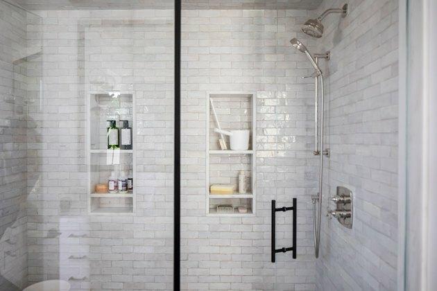 ducha con paredes de azulejos de metro gris claro y puerta de vidrio
