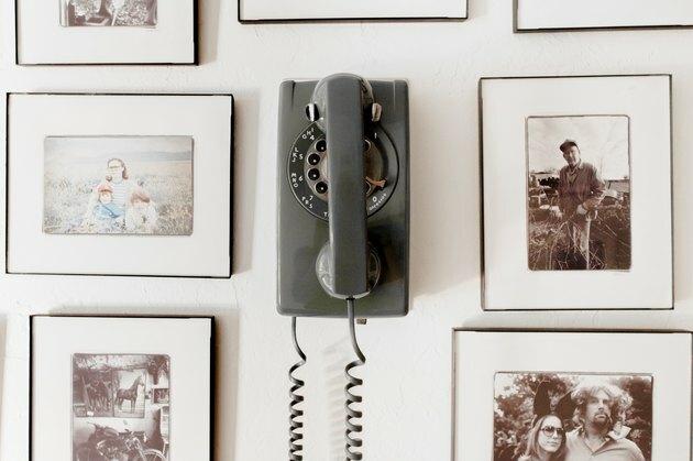 Fotografías personales rodean un teléfono rotativo antiguo.