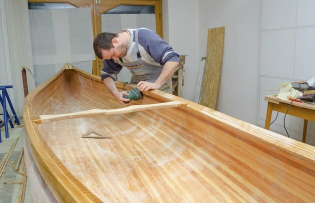 Giovane carpentiere levigatura nuova canoa in officina