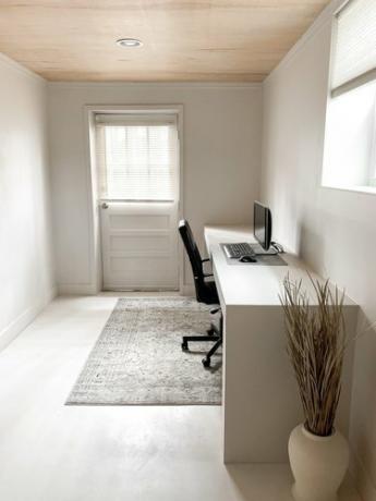minimalistinen kellaritoimisto, jossa on uloskäynti ja moderni työpöytä
