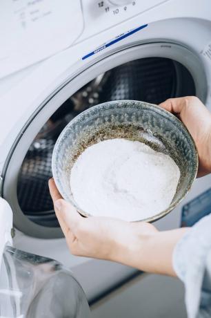 De kom van de handholding met was soda over witte wasmachine