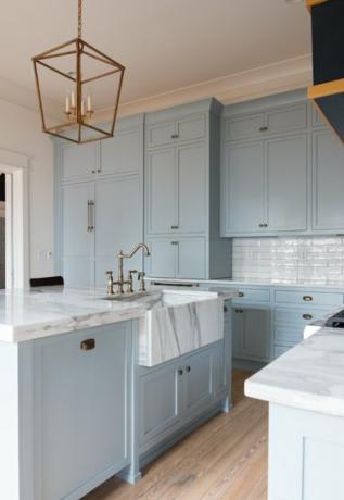 esiliina edessä valkoinen ja harmaa marmorinen keittiön pesuallas sinivalkoisessa maalaistalon keittiössä