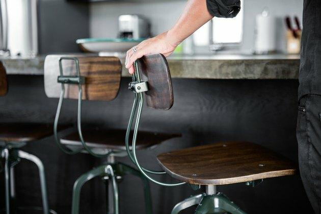 rustieke industriële inrichting met houten en metalen barkrukken in schoolhuisstijl, donkere afwerking.