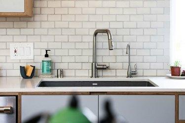 køkkenvask, hvide bordplader, undergrundsfliser og skraldespild