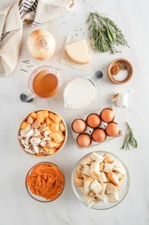 Tutti gli ingredienti disposti su un piano di lavoro in marmo bianco con uno strofinaccio a righe beige, blu e bianche.