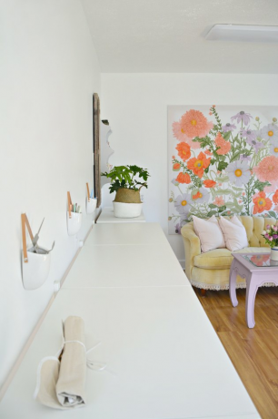 Escritório na garagem com mural floral e estações de trabalho brancas