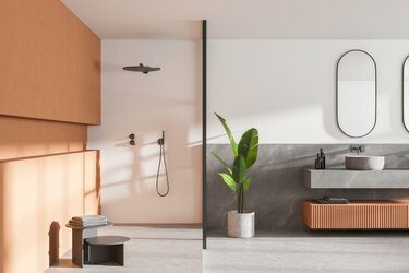Šiuolaikiško vonios kambario su baltomis ir medinėmis sienomis interjeras, betoninės grindys, dviguba kriauklė su dviem veidrodžiais virš jos ir dušo kabina.