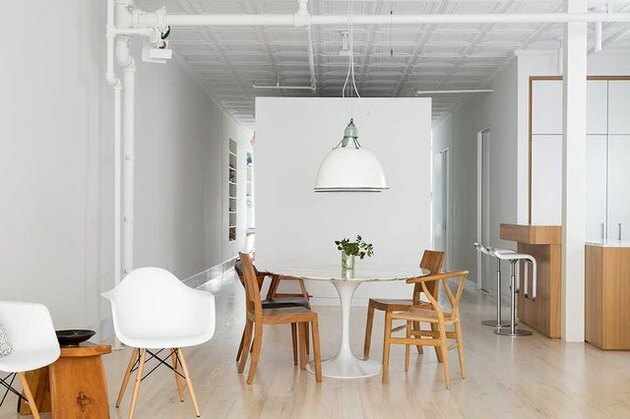 Uma área de jantar foi organizada usando muitos dos móveis anteriores do cliente, incluindo uma mesa Saarinen Tulip, uma luz suspensa recuperada do Plaza Hotel e uma mistura de cadeiras de sala de jantar.
