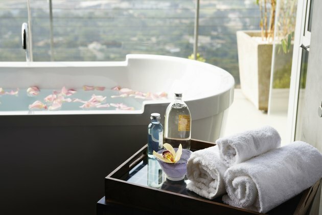 Håndklær, aromatiske oljer og orkide ved siden av badekaret