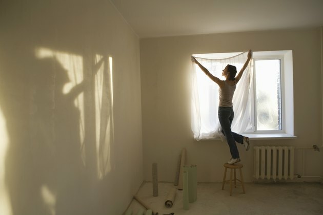 Женщина примеряет шторы в новой квартире