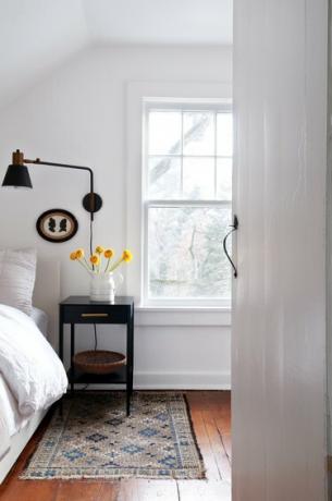 غرفة نوم بجدران بيضاء وأرضيات خشبية مع أثاثات مزرعة داكنة