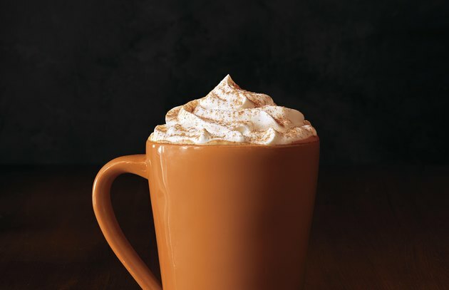 caneca alta de laranja com leite de abóbora com especiarias e creme chantilly