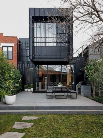 ideia de exterior de casa contemporânea preta com mesas ao ar livre