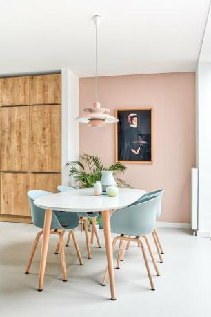 roze eetkamer met lichtblauwe stoelen en roze hanger