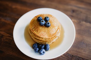 Pannukakkuja vaahterasiirappia ja mustikoita valkoisella lautasella