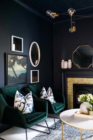 الجدران السوداء في مساحة المعيشة مع الكراسي المخملية الخضراء