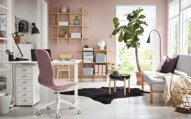 escritório doméstico moderno rosa com plantas e prateleiras montadas na parede, sofá e mesa dobrável