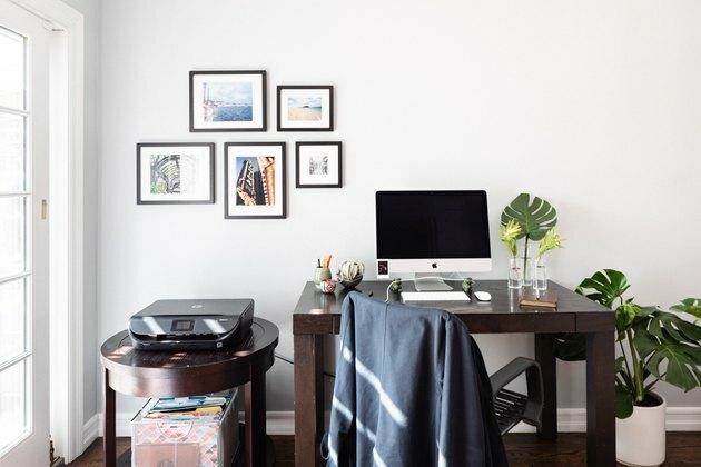 Moderný minimalistický nápad pre malú domácu kanceláriu s malou stenou galérie a dreveným stolom